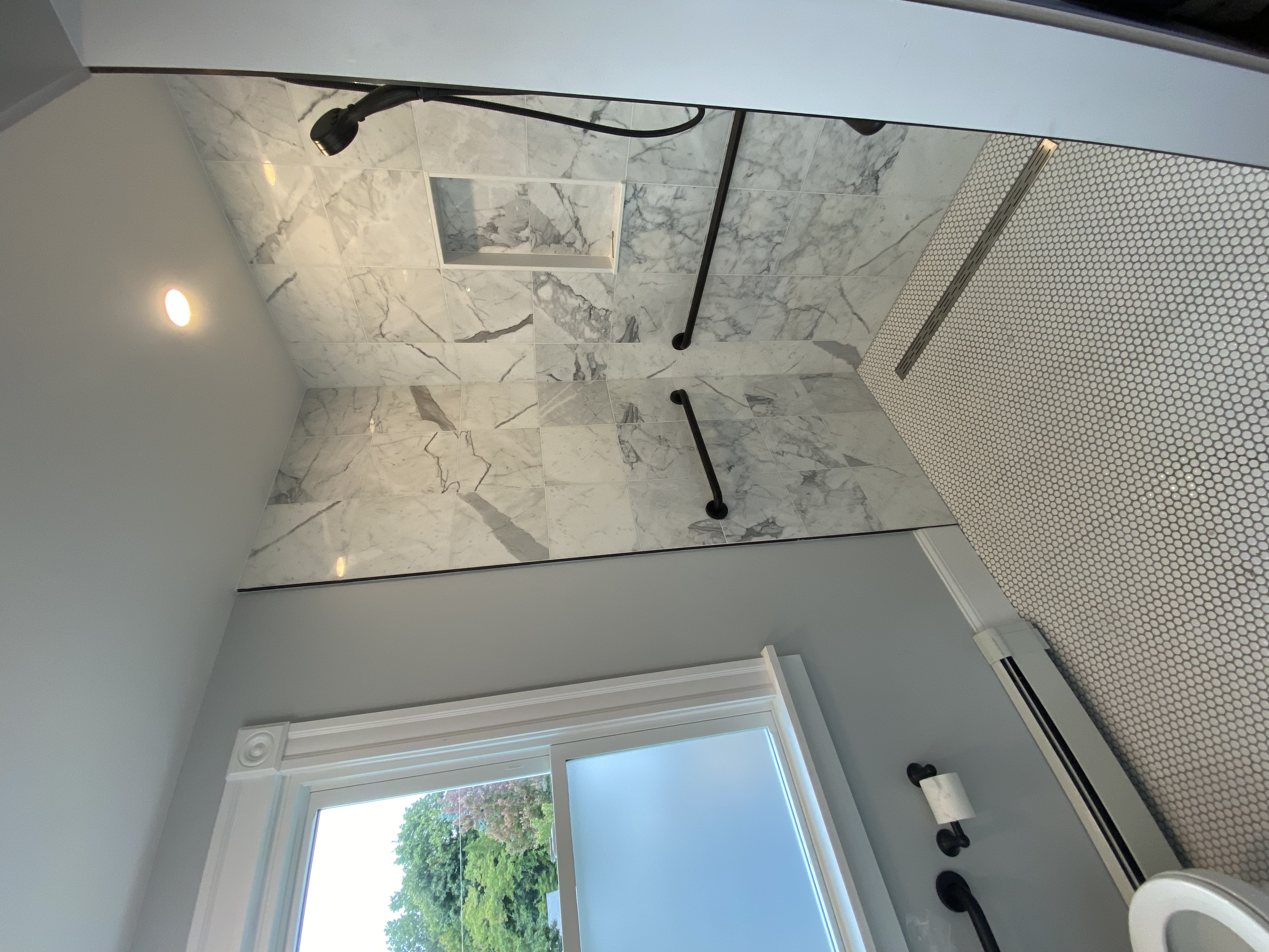 Bathroom shower with marble tile and black fixtures